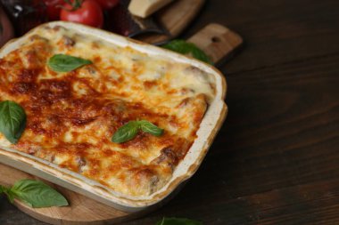 Ahşap masada fesleğen ve fırında pişirilmiş nefis lazanya, yakın plan. Metin için boşluk