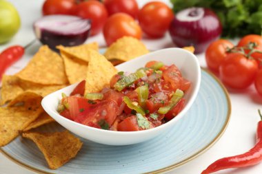 Lezzetli salsa sosu (Pico de gallo) beyaz masada nachos ve ürünlerle servis edilir.