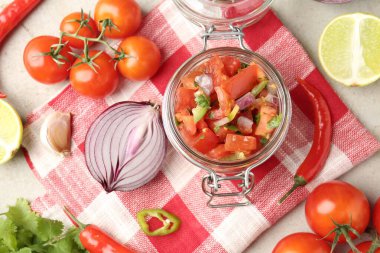 Kavanozda nefis salsa (Pico de gallo) ve açık dokulu masa üzerinde malzemeler, düz yatıyordu.