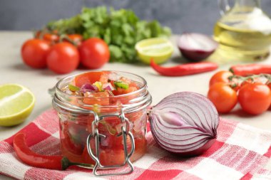 Kavanozda lezzetli salsa (Pico de gallo) ve ışık masasında malzemeler, yakın plan.