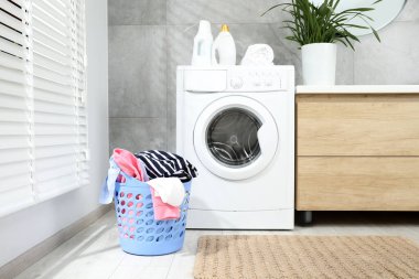 Banyoda yerde çamaşır dolu plastik bir sepet.