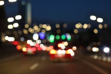 Bulanık şehir manzarası, akşam trafik ve sokak ışıkları.