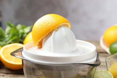 Plastik sıkacağı ve taze portakallar ahşap masada, yakın plan.
