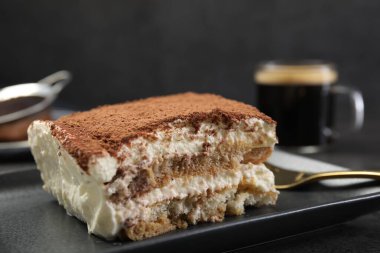 Siyah masanın üzerinde lezzetli bir tiramisu parçası, yakın plan.