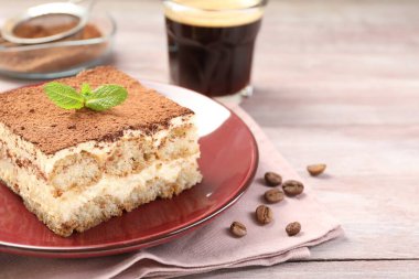 Lezzetli tiramisu tabağı, nane ve kahve çekirdekleri ahşap masada, yakın plan.