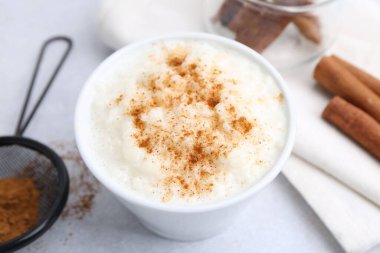 Delicious rice pudding with cinnamon on light table, closeup