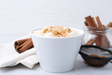 Delicious rice pudding with cinnamon on light table, closeup