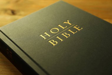 Hardcover Holy Bible on wooden table, closeup