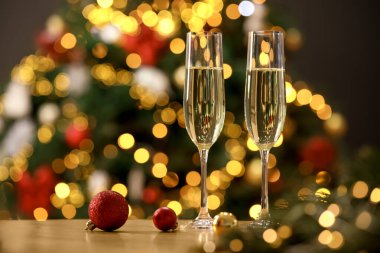 Şampanya bardaklar içinde ve ahşap masada bulanık Noel ışıklarına karşı şenlikli süsler, yazı için yer. Bokeh etkisi