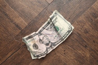 Tahta masanın üzerinde buruşuk bir dolar banknot, üst manzara.