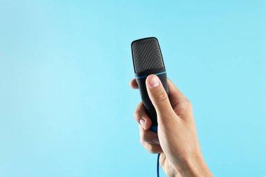 Açık mavi arka planda mikrofonu olan adam, yakın plan. Metin için boşluk