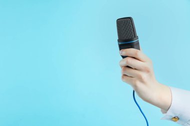 Açık mavi arka planda mikrofonu olan kadın, yakın plan. Metin için boşluk
