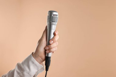 Bej arka planda mikrofonu olan bir kadın, yakın plan. Metin için boşluk