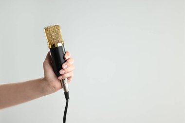 Gri arka planda mikrofonu olan kadın, yakın plan. Metin için boşluk