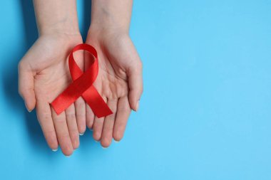 Açık mavi arka planda kırmızı kurdeleli kadın, üst görüş ve yazı için boşluk. HIV (AIDS) Hastalık Bilinci