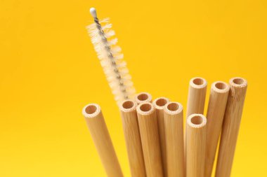 Bambu pipet içmek ve sarı arka planda temizlik fırçası, yakın plan