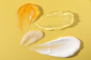 Samples of different cosmetic products on yellow background, above view clipart