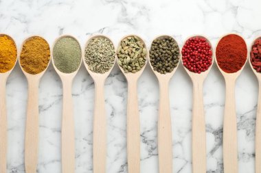 Farklı aromatik baharatlar beyaz mermer masa üzerinde kaşıklar, düz yatıyordu