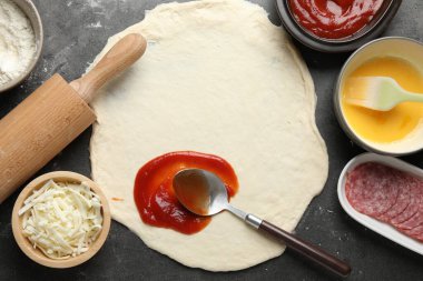 Calzone pizzası yapıyorum. Gri masada soslu ve malzemeli hamur, düz yatıyordu