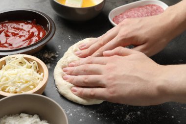 Calzone pizzası yapıyorum. Gri masada parası ve malzemeleri olan kadın, yakın plan.