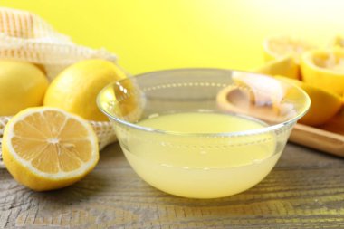 Taze limon suyu ve ahşap masada meyveli kase, yakın plan.