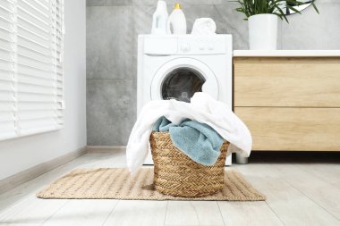 Wicker basket full of laundry on floor in bathroom clipart