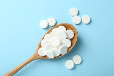Antibiyotik haplar ve açık mavi arka planda kaşık, düz uzanma