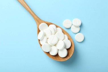 Antibiyotik haplar ve açık mavi arka planda kaşık, düz uzanma