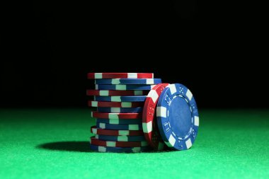 Poker çipleri yeşil masa üzerinde koyu arkaplan, yakın plan
