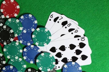 Yeşil masada kağıt ve poker fişleri düz yatıyordu.