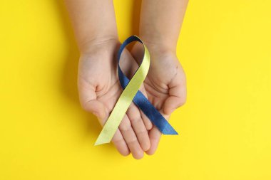 Arka planda sarı ve mavi kurdeleli çocuk, üst manzara. Down sendromu farkındalığı