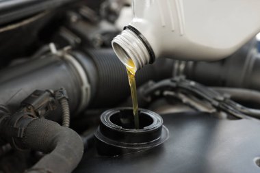Araba motoruna motor yağı dökülüyor, yakın plan.