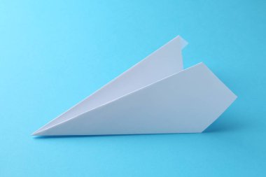 Açık mavi arkaplanda bir el yapımı kağıt uçak