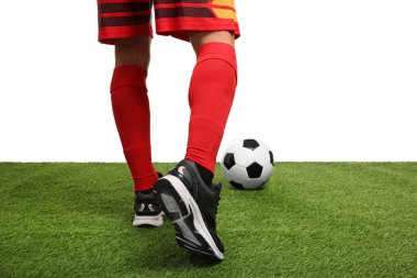 Beyazların arka planına karşı suni çimlerde futbol topu taşıyan futbolcu, yakın plan