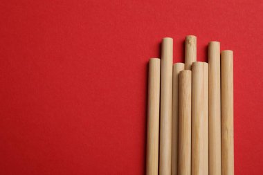 Kırmızı arka planda bambu pipetleri, üst manzara. Metin için boşluk