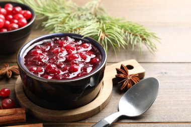 Lezzetli kızılcık sosu, böğürtlen, baharat ve köknar ağacı dalları ahşap masada, yakın plan.