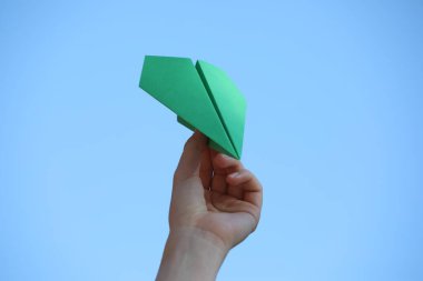 El yapımı kağıt uçakla açık havada gökyüzüne karşı duran kadın, yakın plan.