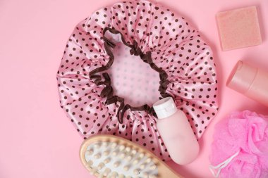 Pembe arka planda duş bonesi ve banyo aksesuarları, düz uzanma