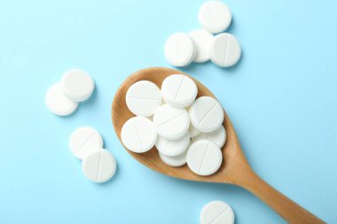 Antibiyotik haplar ve açık mavi arka planda kaşık, düz uzanma