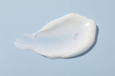 Açık mavi arka planda krem örneği, yakın plan. Kozmetik ürünü
