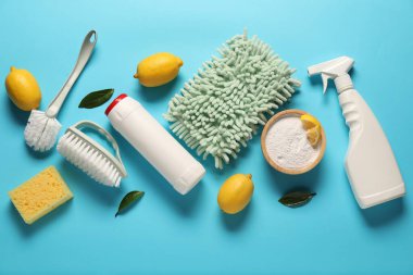 Açık mavi zemin üzerinde temizlik ürünleri, araçlar ve limonlar, düz uzanma