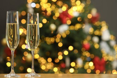 Ahşap masanın üzerinde, bulanık Noel ışıklarına karşı şampanya, mesaj için yer. Bokeh etkisi
