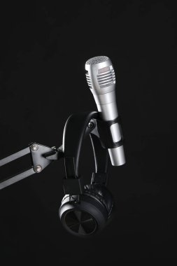 Siyah arka planda mikrofon ve kulaklıkla bekle. Ses kaydı ve takviye