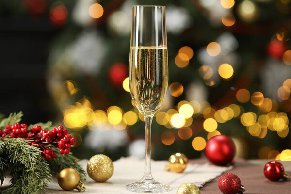 Шампанское в стакане и декор на столе против размытых рождественских огней, эффект боке