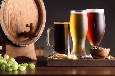 Farklı tipte bira, fıçı, aperatif ve ahşap masada taze zıpzıp bardakları.