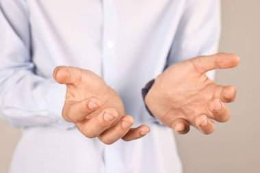 Gri arkaplanda bir şey tutan adam, yakın plan.