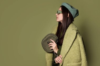 Zeytin arka planında şık aksesuarları olan genç bir kadın.