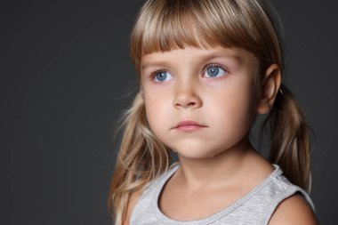 Yetimhane konsepti. Gri arka planda üzgün küçük bir kız