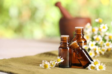 Gerekli yağ şişeleri ve kumaş üzerinde papatya çiçekleri. Metin için boşluk