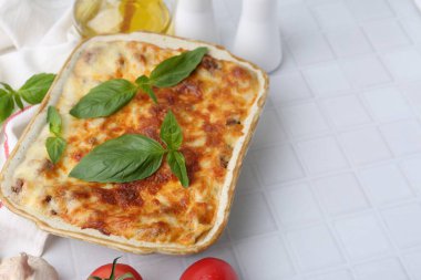 Beyaz fayanslı masada servis edilen fesleğenli nefis pişmiş lazanya, yakın plan. Metin için boşluk